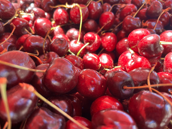 Close-up of a pile of red cherries with stems.